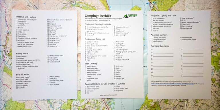 A printed camping essentials checklist lying on a hiking map