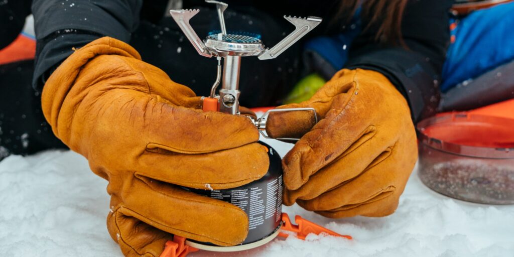 A camper changing a Jetboil Jetpower fuel canister on a Jetboil MightyMo camping stove in winter