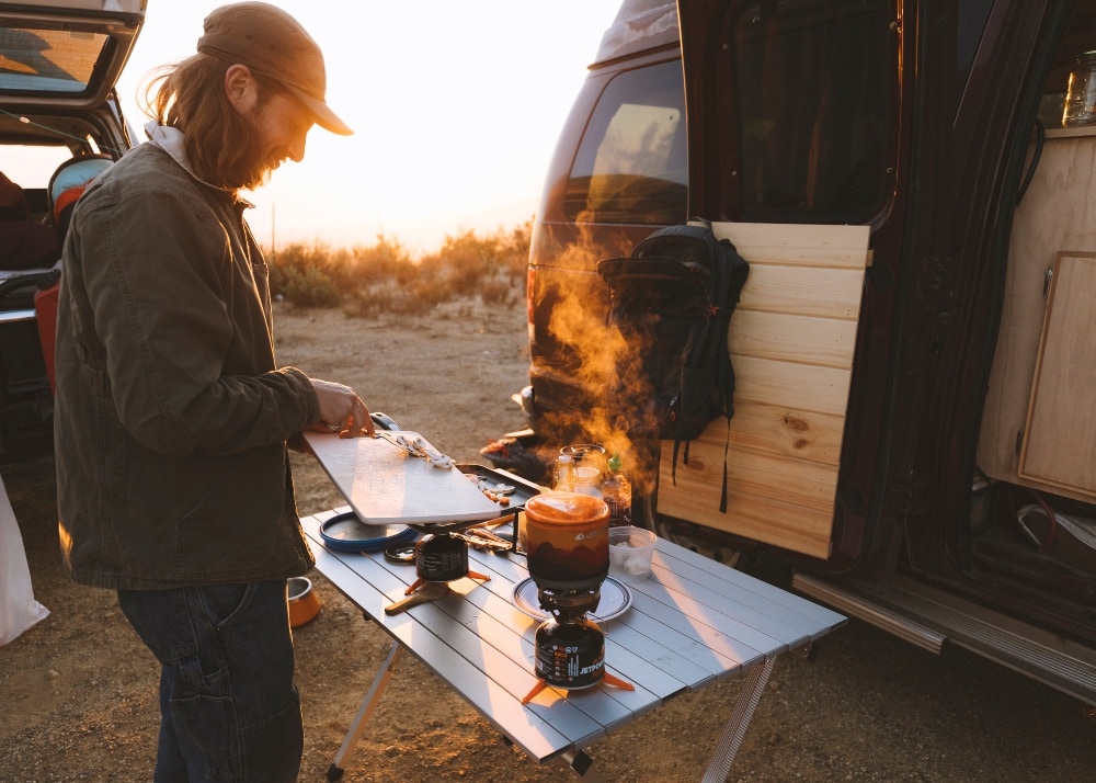 Man putting chopped mushrooms into a jetboil minimi backpacking stove at a campsite
