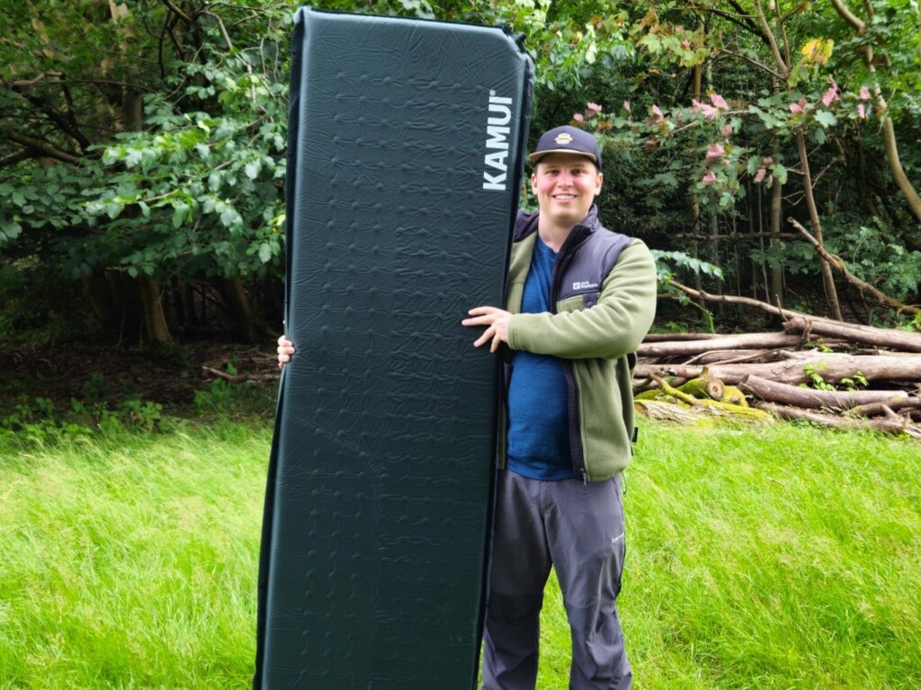 Camper holding a camping mattress in our kamui sleeping mat review