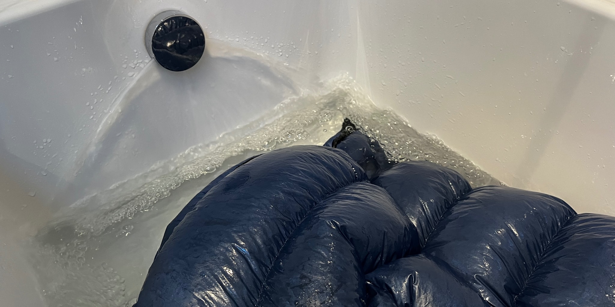 bathtub with sleeping bag inside it being refilled with water