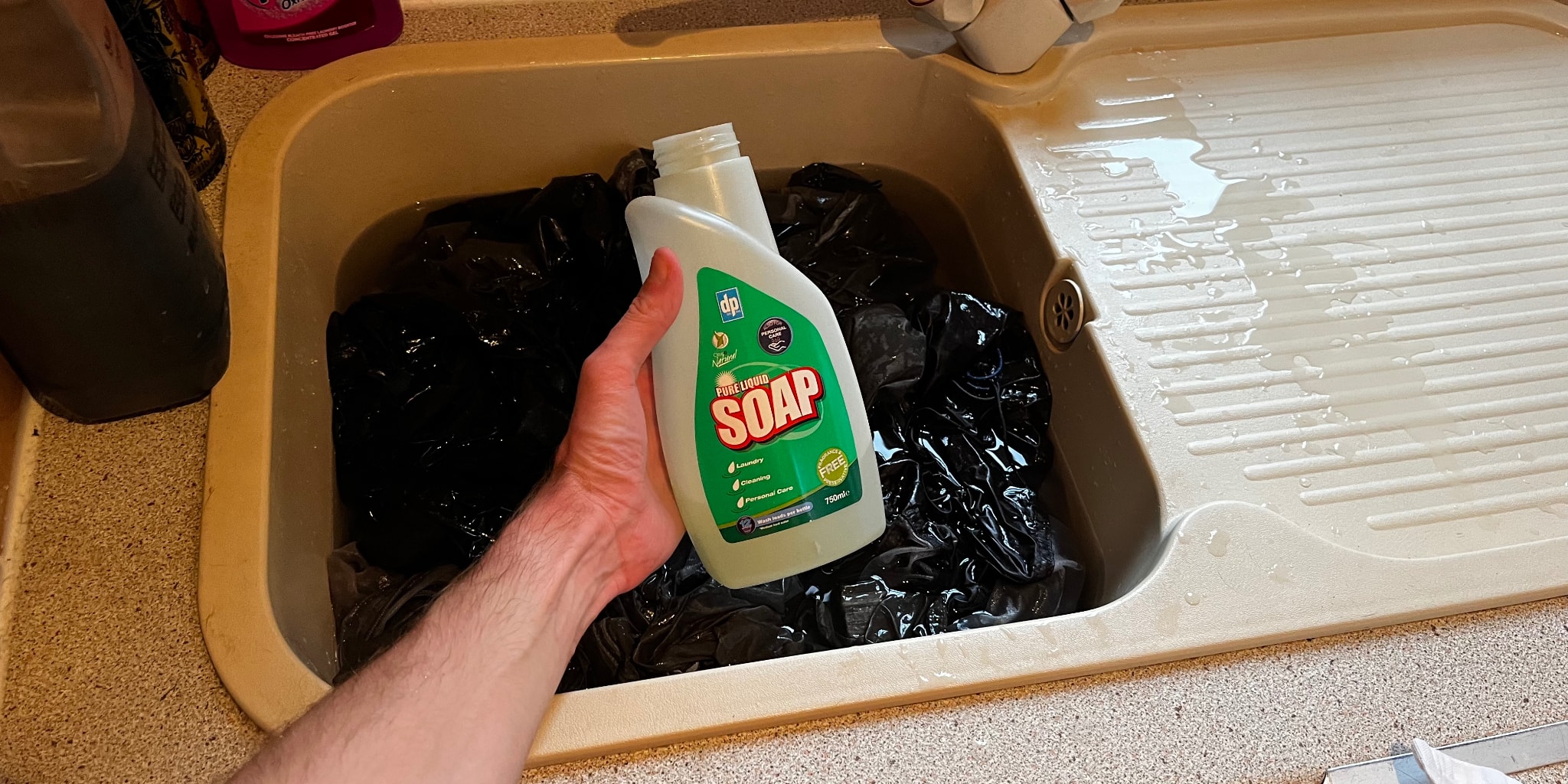 Someone holds liquid soap in hand above basin