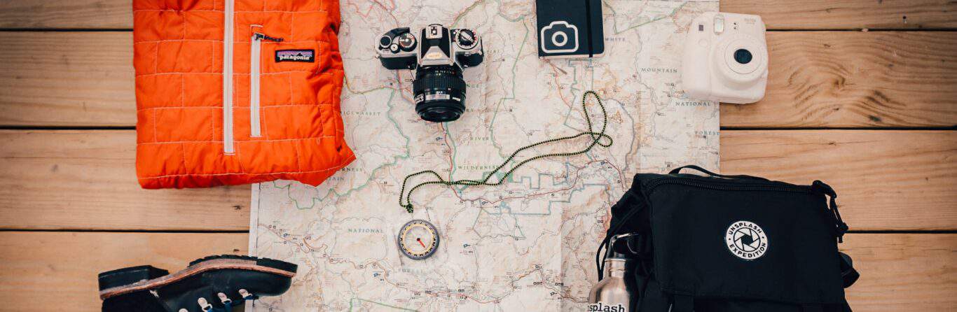 A backpack and boots with some of the essentials like a map and compass