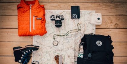 A backpack and boots with some of the essentials like a map and compass
