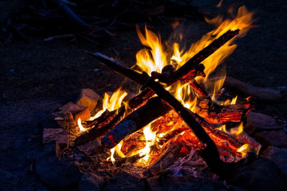 A small campfire surrounded by a fire ring at night