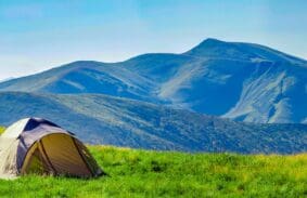 A tent pitched in front of rolling hills