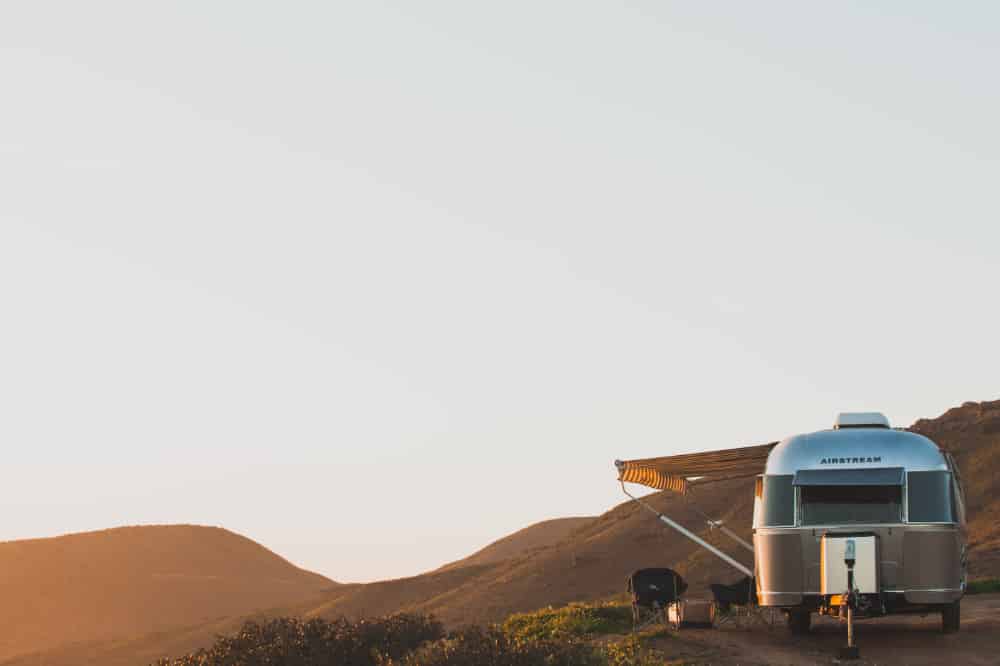 A glamping Airstream trailer looking out over rolling hills 