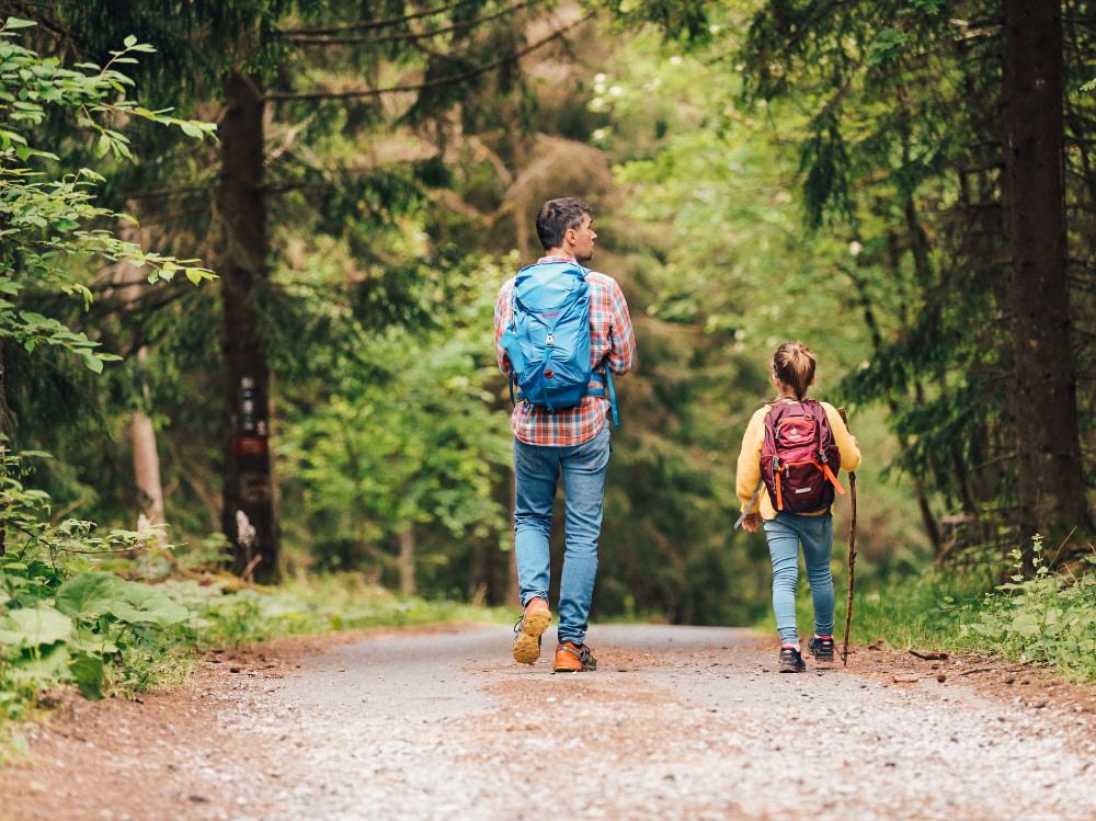 A father and daughter hike in the woods