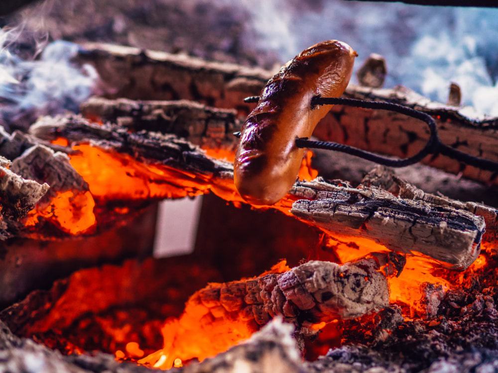 A sausage being cooked over an open fire