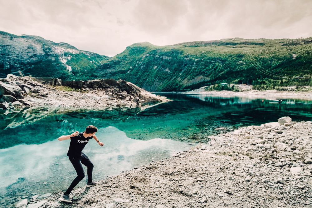 A teenager skimming stones on a lake 