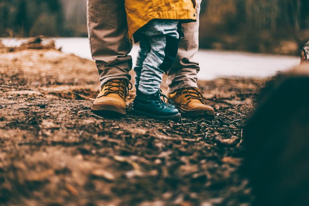 A toddler stood in front of an adult's legs