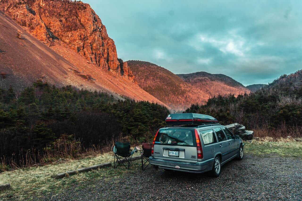 A car and two chairs with mountains in the background.