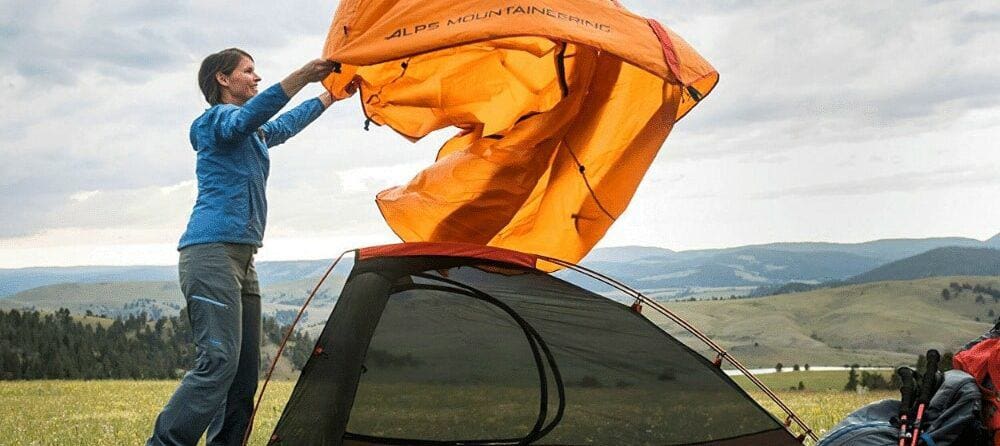 A woman setting up the ALPS Mountaineering Zephyr tent, the best 2 person backpacking and camping budget tent when it comes to storage.