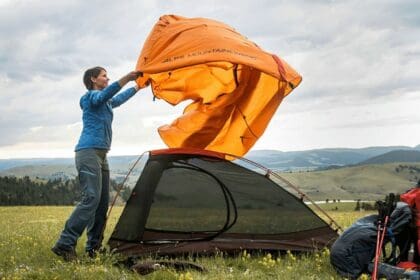 A woman setting up the ALPS Mountaineering Zephyr tent, the best 2 person backpacking and camping budget tent when it comes to storage.
