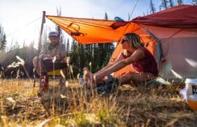 Two campers sat by their Big Agnes Copper Spur backpacking tent with the vestibule open