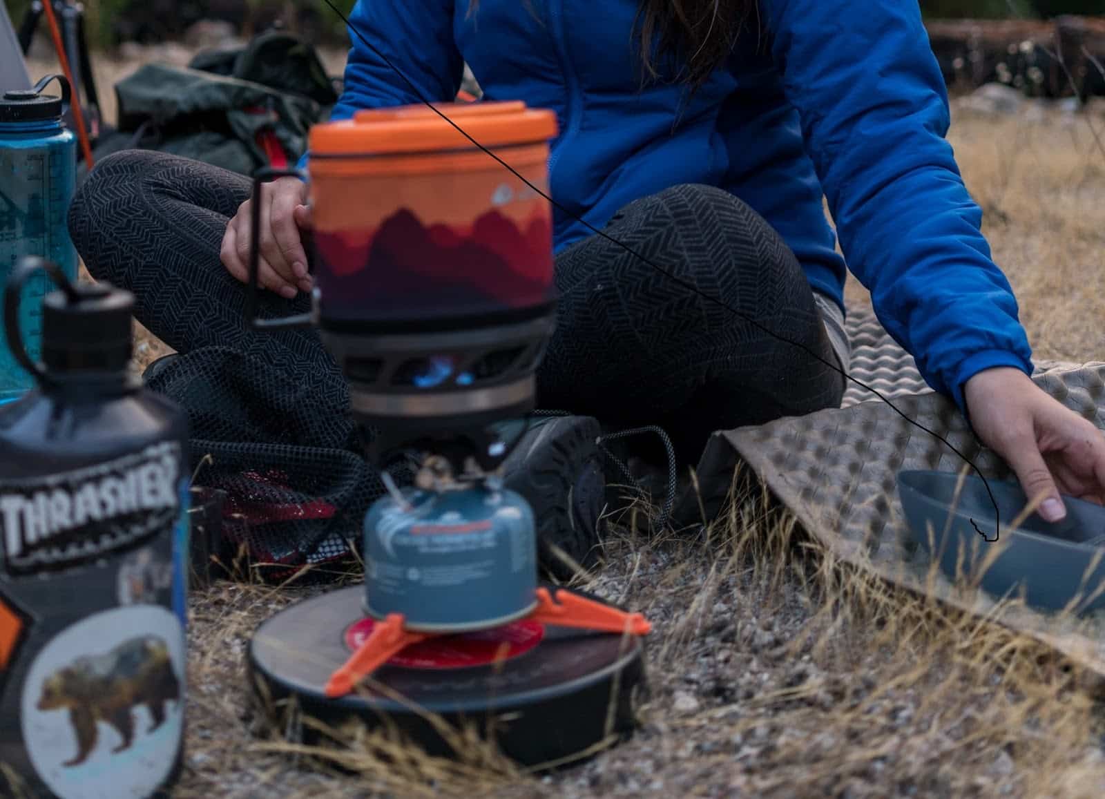 Person sitting on the ground with a Jetboil stove.