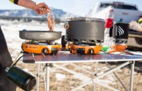 Man frying bacon outdoors on his Jetboil Genesis camping stove