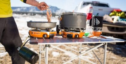 Man frying bacon outdoors on his Jetboil Genesis camping stove