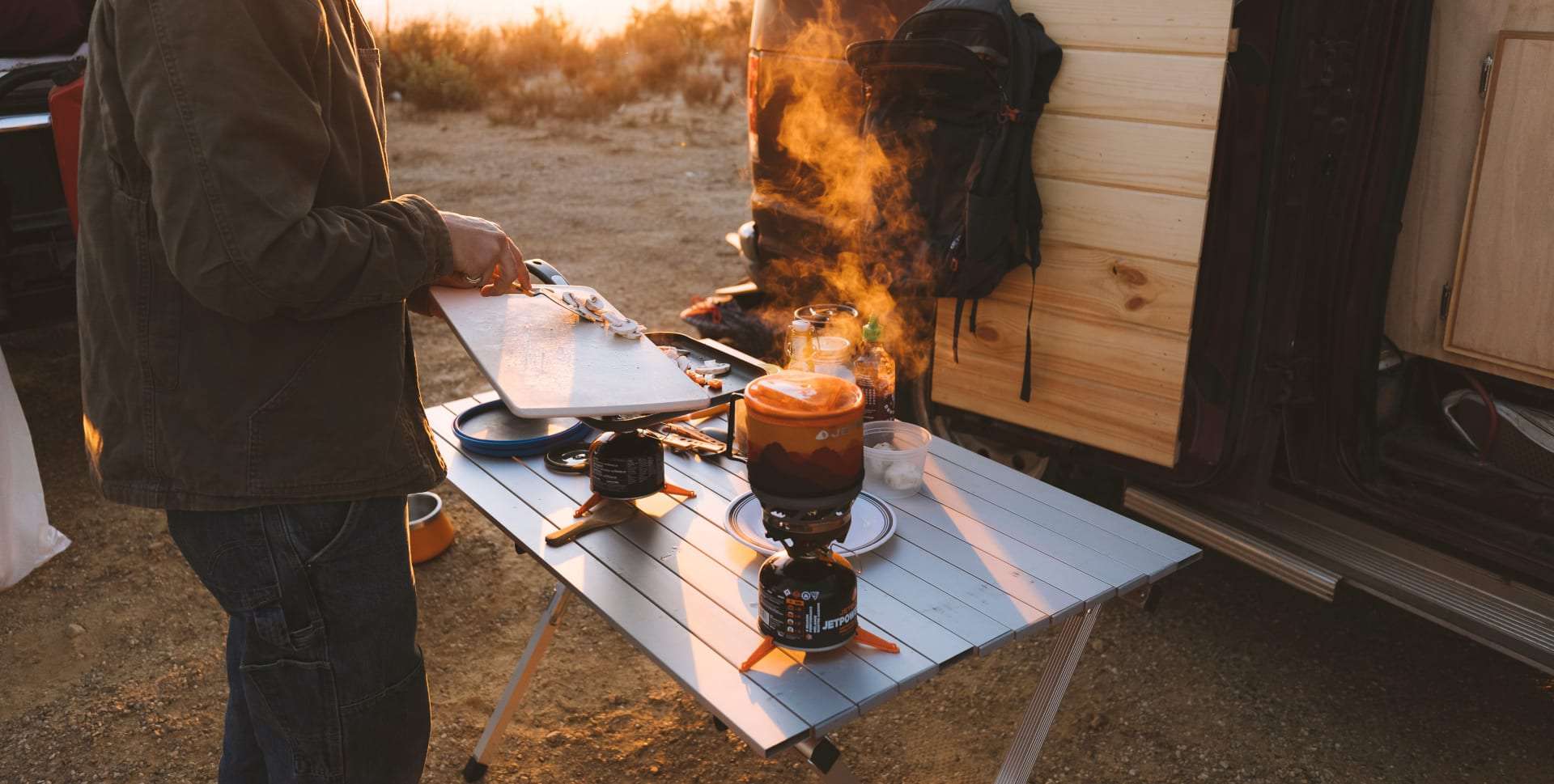 The Jetboil MiniMo camping stove cooking while a man chops vegetables for the meal