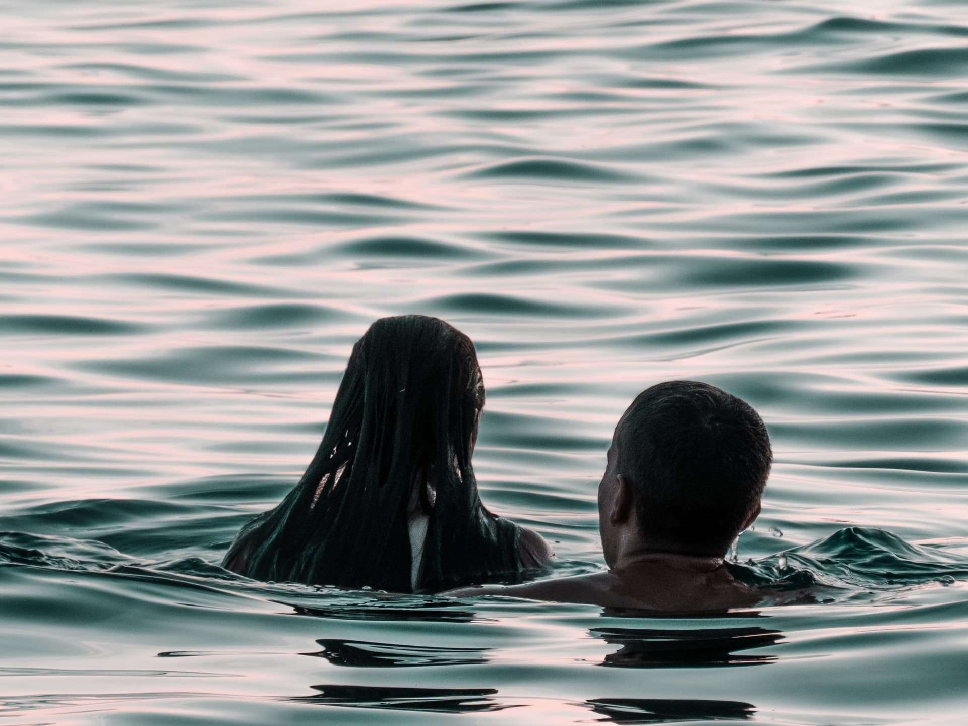 A couple swimming near their campsite on dusk in a lake