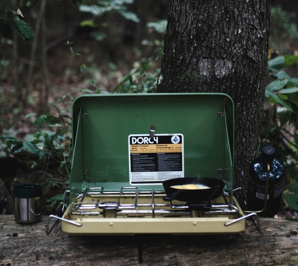 Portable camp stove on a log in the forest