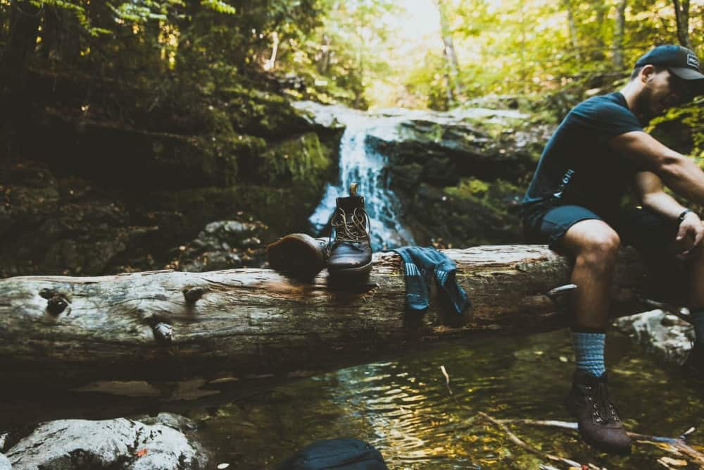 Wet hiking boots on a log by a waterfall