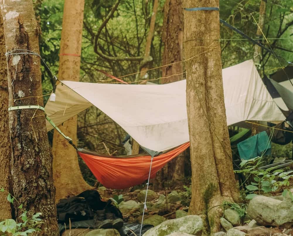 A tarp set up over a camping hammock to protect the shelter from rain