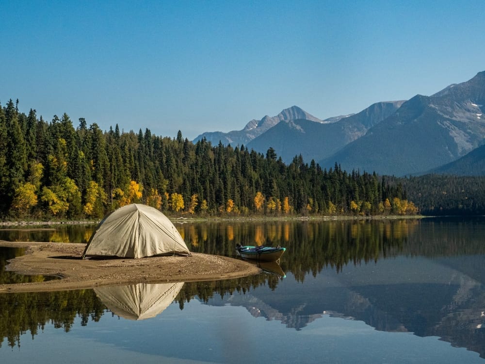 Tent set up on a lake edge with a canoe in the water