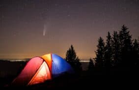 A red color tent, blue color tent and orange color camping tent set up at night under a starry sky