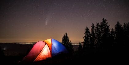 A red color tent, blue color tent and orange color camping tent set up at night under a starry sky
