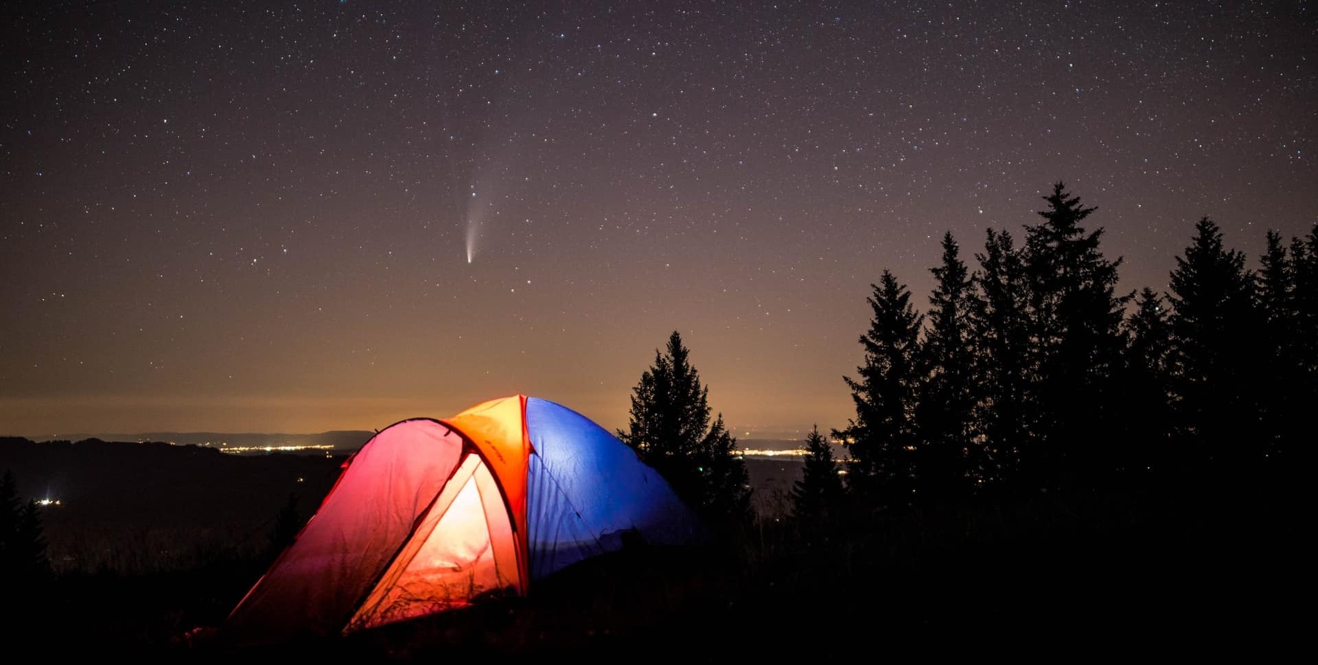 A red, blue and orange color camping tent set up at night under a starry sky