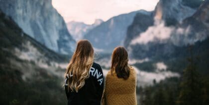 Two girls looking across a mountain scene wrapped up warm at Dawn.