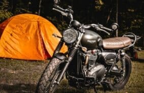 Triumph motorcycle outside an orange motorcycle camping tent in a campsite