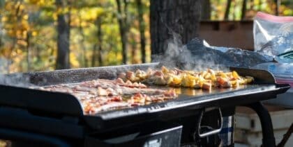 Bacon and potatoes cooking on an outdoor camping griddle