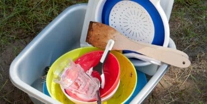 A camping sink full of dirty dishes to wash