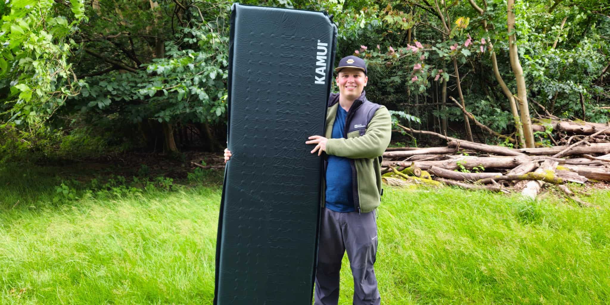 Camper holding a camping mattress in our Kamui sleeping pad review